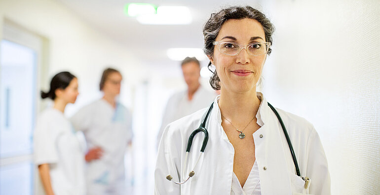 Ärztin steht vor Ihrem Team in der Klinik