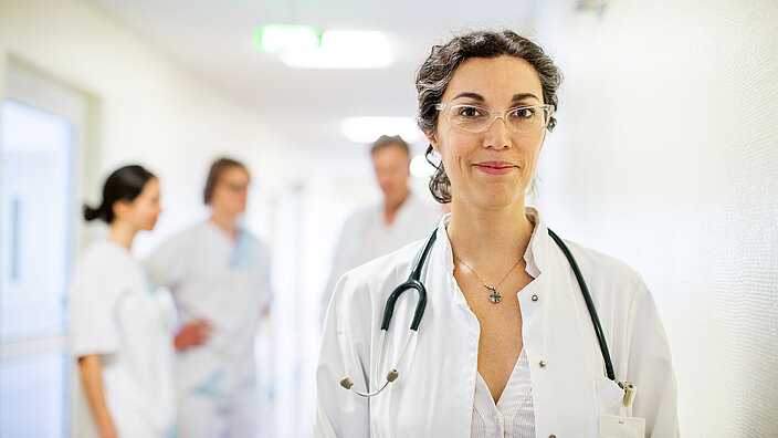 Ärztin steht vor Ihrem Team in der Klinik